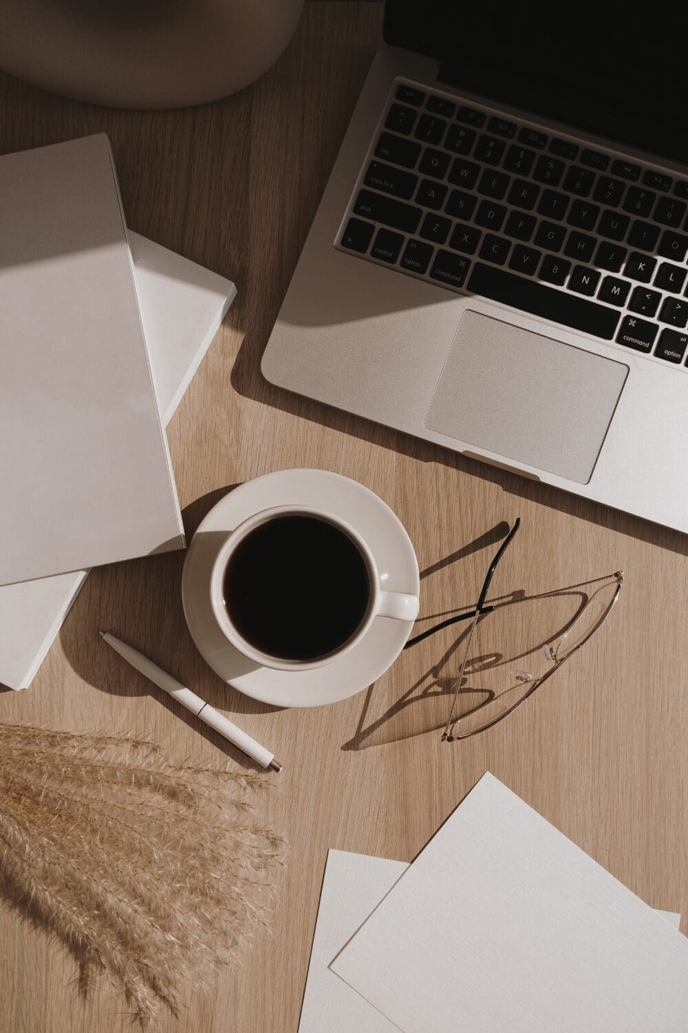 Working on a laptop and coffee and notepad, representing the role of a virtual yacht purser working shoreside.